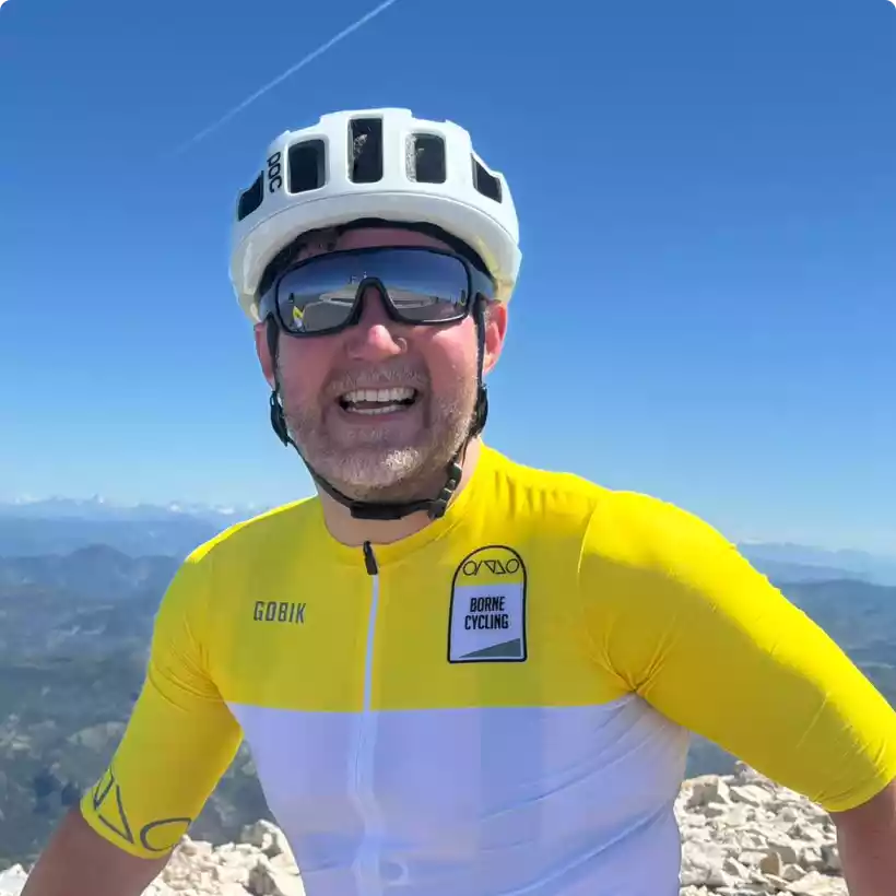 Cyclist Paul Munn is smiling at the camera with a view from Mont Ventour in the background.