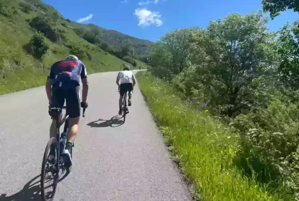 cyclists climbing mountain road blue sky